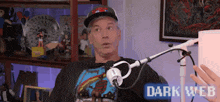 a man is sitting in front of a microphone with the words dark web on the bottom of the screen .