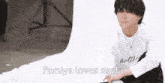 a man in a white shirt is sitting in front of a white background with the words fumiya loves seela below him