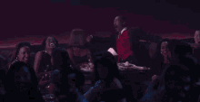 a man in a red vest is sitting at a table with a lamp