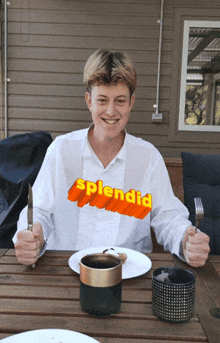 a man wearing a shirt that says splendid sits at a table holding a knife and fork