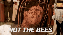 a man is in a cage with bees on his face and the words `` not the bees '' written on the bottom .