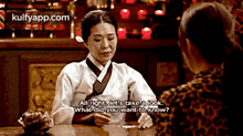 a woman in a kimono is sitting at a table talking to another woman in a leopard print shirt .