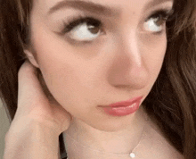 a close up of a woman 's face wearing a necklace and looking up .