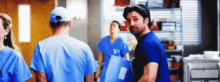 a group of doctors and nurses standing in a hospital room .