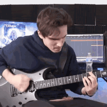 a man playing a guitar in front of a monitor that says nocturnal on it