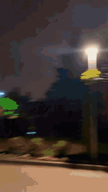 a blurred image of a street at night with a street light in the foreground