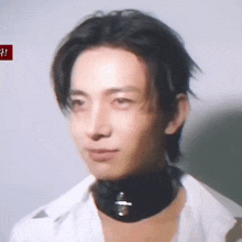 a man wearing a white shirt and a black choker around his neck .