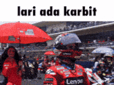 a lenovo motorcycle racer is standing in front of a crowd holding an umbrella
