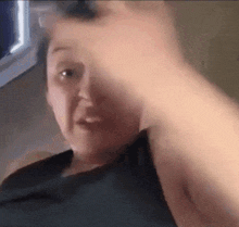a woman in a black tank top is holding a gun in her hand