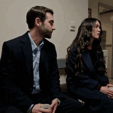 a man and a woman sit next to each other in front of a sign that says fire exit