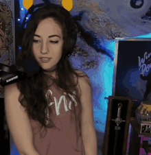 a woman wearing headphones and a pink tank top that says ' ania ' on it