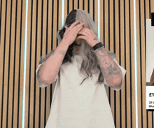 a man with a tattoo on his arm covering his face with his hands