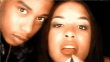 a man and a woman are posing for a picture and the woman is applying lipstick