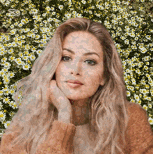 a woman is standing in a field of daisies with her hand on her chin