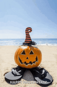 a pumpkin wearing a witch hat is sitting on a pair of flip flops on the beach
