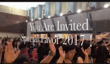 a group of people raising their hands in front of a sign that says you are invited