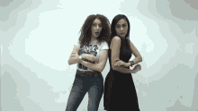 two women are standing next to each other with their arms crossed . one of the women is wearing a star wars shirt .