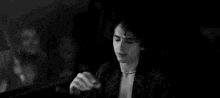 a black and white photo of a young man smoking a cigarette .