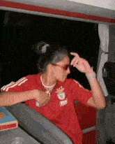 a woman wearing sunglasses and a red shirt that says benfica on it