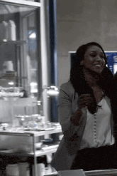 a woman in a white shirt and gray jacket is standing in a room with a glass case .