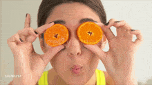 a woman covering her eyes with sliced oranges