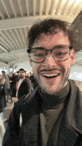 a man with glasses and a beard is smiling in front of a crowd