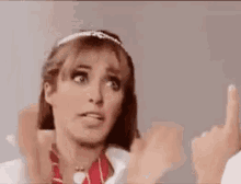 a woman is giving a thumbs up sign while wearing a headband .