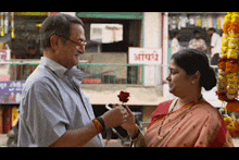 a man is giving a rose to a woman in front of a sign that says ' a '