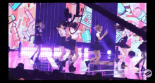 a group of girls are dancing on a stage in front of a large screen .