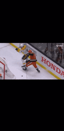 two hockey players are fighting on the ice in front of a honda advertisement