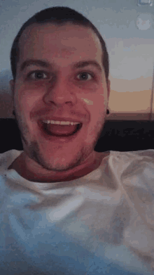 a man with a white shirt on is smiling with his tongue out