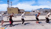 a group of people are dancing in a video game on a rooftop .