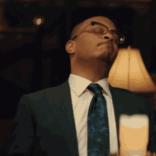 a man in a suit and tie is standing in front of a lamp with his eyes closed
