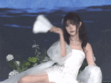 a woman in a white dress holding a fan