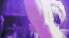 a close up of a person 's head with purple lights behind them .