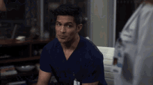 a man in a blue scrub top has a name tag on his neck that says ' dr. '