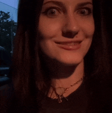 a close up of a woman 's face with a heart shaped necklace
