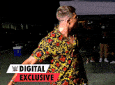 a man in a floral shirt stands in front of a sign that says w digital exclusive