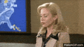 a woman is sitting in front of a screen that shows the weather