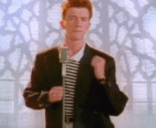 a man in a suit and tie is singing into a microphone in front of a stained glass window .