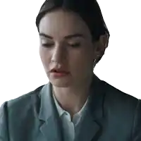 a woman in a grey suit and white shirt looks down with her eyes closed