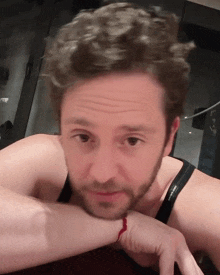 a man with a beard wears a black tank top with the word victoria 's secret on it