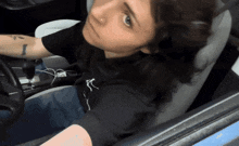 a woman with a tattoo on her arm is sitting in the driver 's seat
