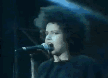 a woman with a big afro is singing into a microphone on a stage .