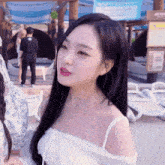a girl with long black hair is wearing a white off the shoulder top