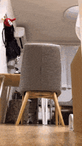 a gray chair sits in a room next to a table and a fan