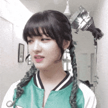 a girl with braids and a green jacket is standing in a hallway with the number 18 on the wall