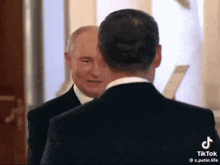 a man in a suit and tie is talking to another man in a suit and tie
