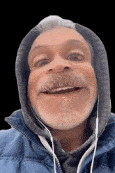 a man with a beard wearing a blue jacket and headphones makes a funny face