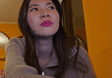 a woman wearing a grey sweater and pink lipstick